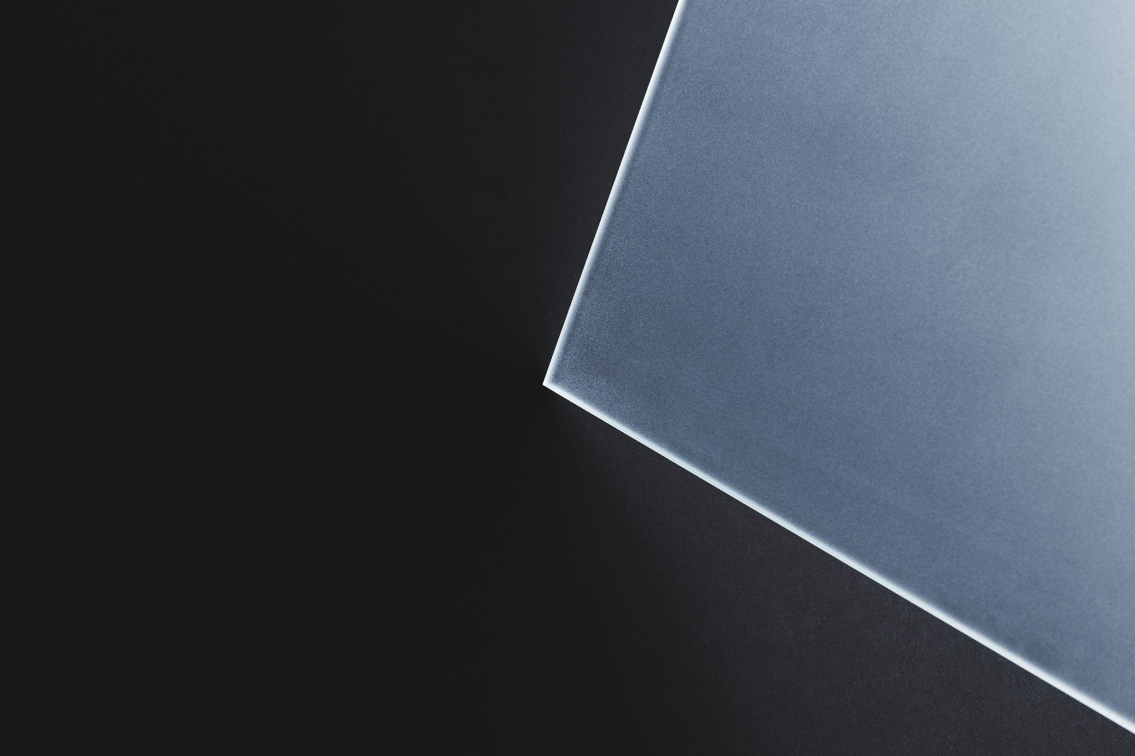 Dunne matte glasplaat met scherpe rand op donkere achtergrond, minimalistisch en modern ontwerp